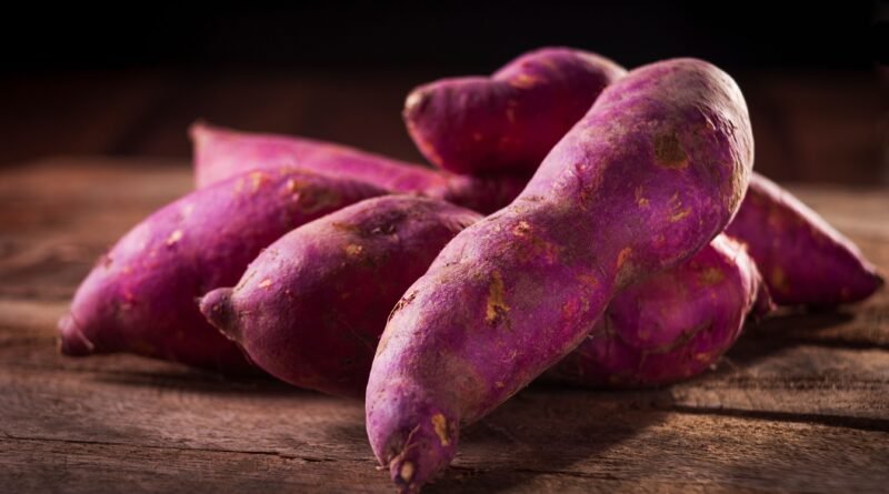 Older adult preparing colorful sweet potatoes and vegetables for a balanced healthy meal