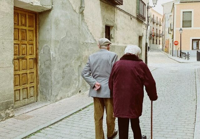 Older adult walking with support during a supervised mobility and strength exercise session.