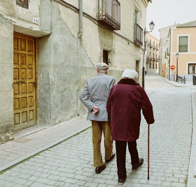 Older adult walking with support during a supervised mobility and strength exercise session.