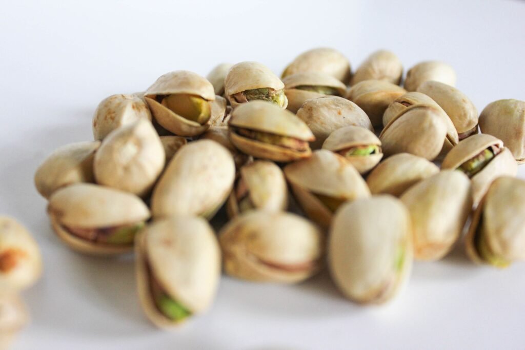 Open pistachio shells and green pistachio kernels in a bowl, highlighting this nutrient-rich plant-based snack.