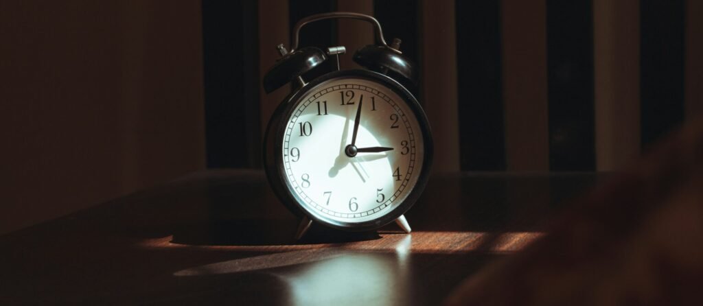 Person sitting beside a bedroom window in the morning, illustrating the relationship between sleep timing, daylight and mental health.