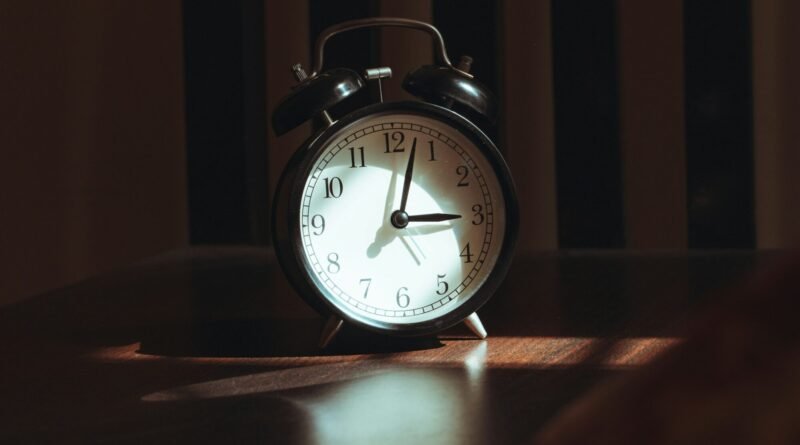 Person sitting beside a bedroom window in the morning, illustrating the relationship between sleep timing, daylight and mental health.